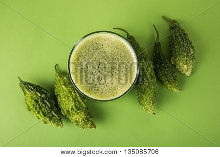 Herbal juice of green momodica in a glass with sliced vegetables, karela juice or bitter gourd juice