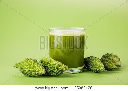 Herbal juice of green momodica in a glass with sliced vegetables, karela juice or bitter gourd juice