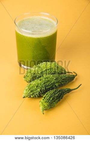 Herbal juice of green momodica in a glass with sliced vegetables, karela juice or bitter gourd juice