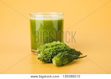 Herbal juice of green momodica in a glass with sliced vegetables, karela juice or bitter gourd juice