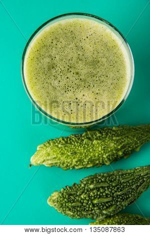 Herbal juice of green momodica in a glass with sliced vegetables, karela juice or bitter gourd juice