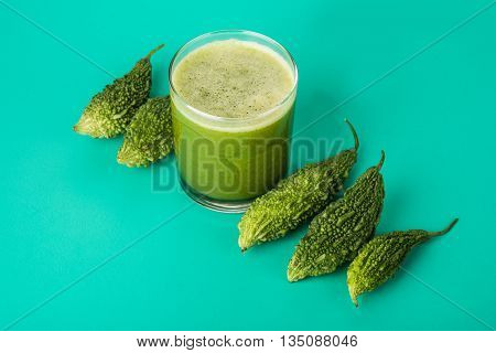 Herbal juice of green momodica in a glass with sliced vegetables, karela juice or bitter gourd juice