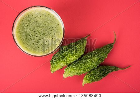 Herbal juice of green momodica in a glass with sliced vegetables, karela juice or bitter gourd juice