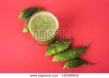 Herbal juice of green momodica in a glass with sliced vegetables, karela juice or bitter gourd juice