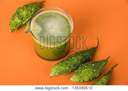 Herbal juice of green momodica in a glass with sliced vegetables, karela juice or bitter gourd juice