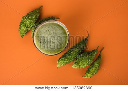 Herbal juice of green momodica in a glass with sliced vegetables, karela juice or bitter gourd juice