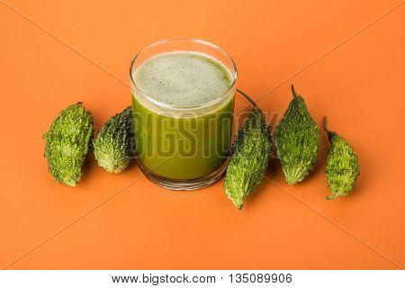 Herbal juice of green momodica in a glass with sliced vegetables, karela juice or bitter gourd juice