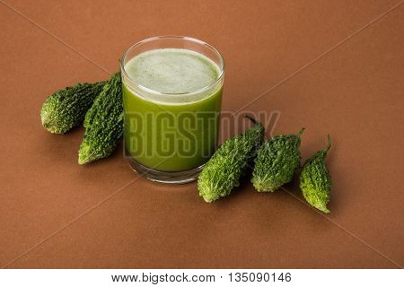 Herbal juice of green momodica in a glass with sliced vegetables, karela juice or bitter gourd juice