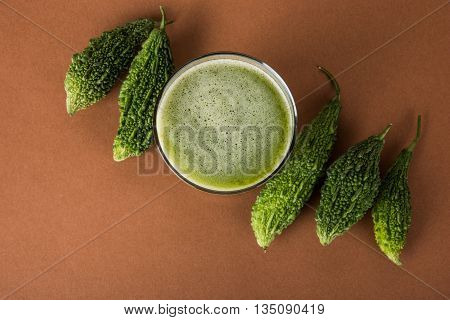 Herbal juice of green momodica in a glass with sliced vegetables, karela juice or bitter gourd juice
