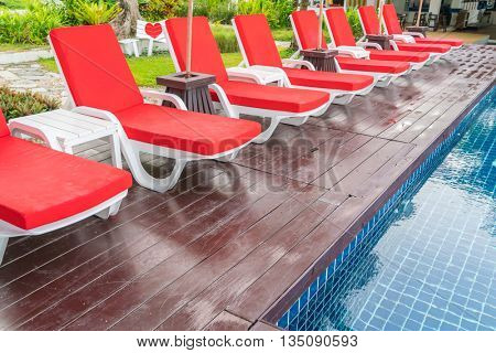 Beautiful beach chairs with umbrella around outdoor swimming pool neary sand and sea