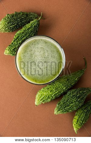 Herbal juice of green momodica in a glass with sliced vegetables, karela juice or bitter gourd juice