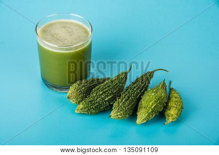 Herbal juice of green momodica in a glass with sliced vegetables, karela juice or bitter gourd juice