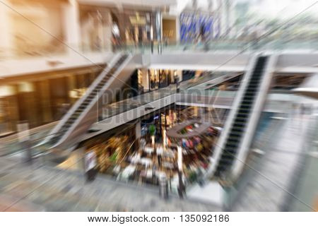 The abstract blurred people inside the shopping mall; filter radial blur zoom effect.