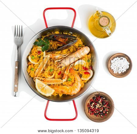 Top view of spanish paella with shrimp and mussel served with olive oil and spices isolated on white background.
