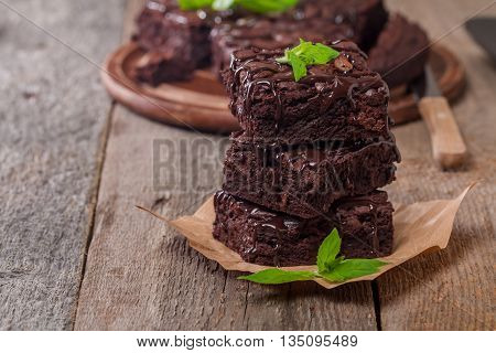 Delicious chocolate brownie with mint on wooden table.