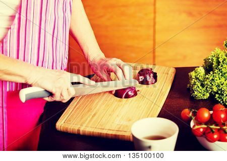 Woman cut red onion on cutting board