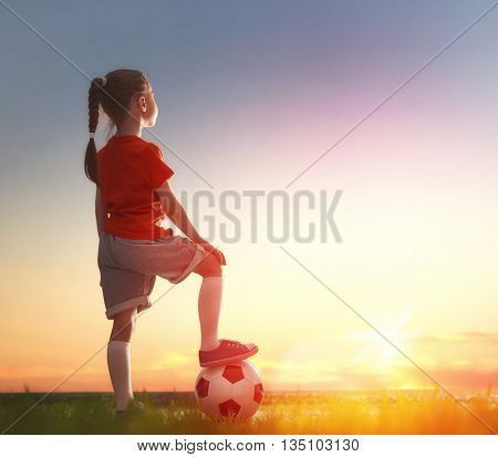 Cute little child dreams of becoming a soccer player. Girl plays football.