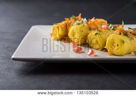 khandvi is a gujarati snack from India which is made with gram flour and curds tempered with sesame seeds and mustard seeds also known as Surali chya Vadya/Stuffed Khandvi, selective focus