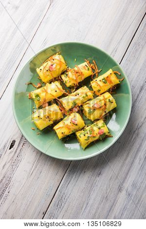 khandvi is a gujarati snack from India which is made with gram flour and curds tempered with sesame seeds and mustard seeds also known as Surali chya Vadya/Stuffed Khandvi, selective focus