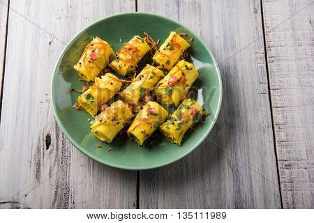 khandvi is a gujarati snack from India which is made with gram flour and curds tempered with sesame seeds and mustard seeds also known as Surali chya Vadya/Stuffed Khandvi, selective focus