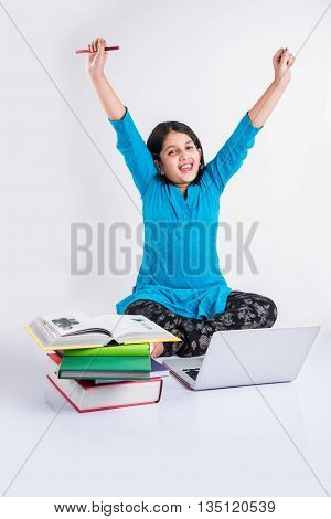 ute little indian girl studying on laptop, asian small girl studying and using laptop, innocent indian girl child and study concept with pile of books & laptop