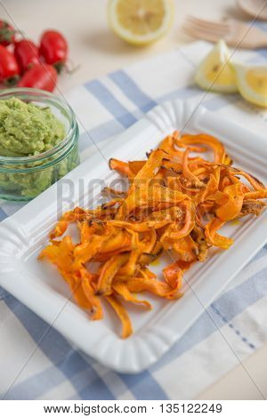 Healthy organic carrot vegetable chips with guacamole dip