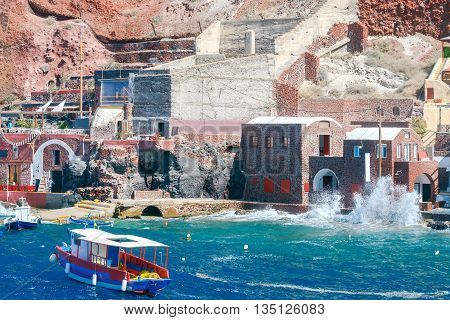 Big waves in water area the old harbor Oia village.
