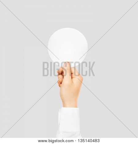 Hand holding round blank white sticker mock up isolated on gray. Sticker mockup holder. Empty paper clue remnder hold in hands.