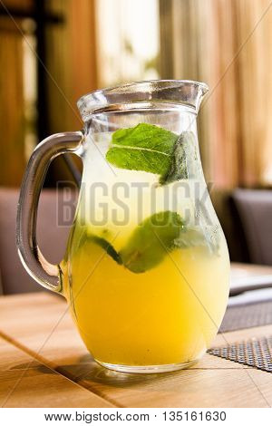 A refreshing drink in a jar on the table. Chilled juice with ice and mint