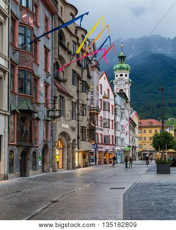INNSBRUCK AUSTRIA - 18TH JUNE 2016: A view along Maria-Theresien-Strasse in Innsbruck during the day. The Hospital Church and the outside of buildings can be seen. Mountain can be seen in the distance.