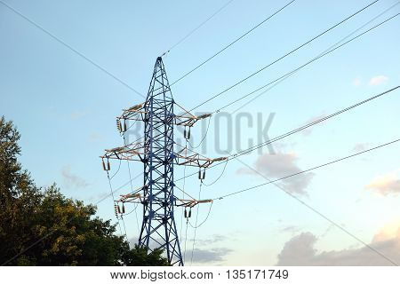 High-voltage power line metal prop with wires over cloudy blue sky in the evening horizontal view