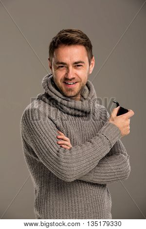Man laughing with a pipe in his hand, studio, gray background.