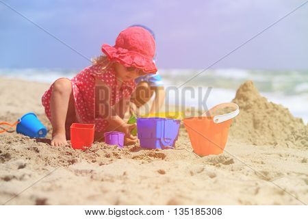kids play with sand on summer beach, family vacation