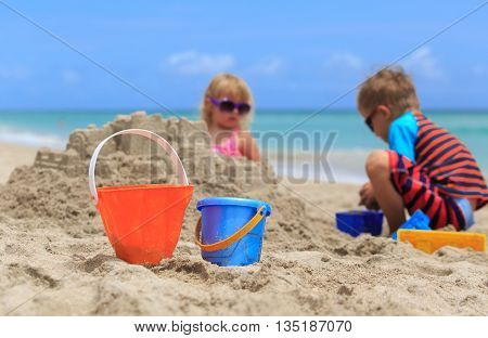kids play with sand on summer beach, family vacation