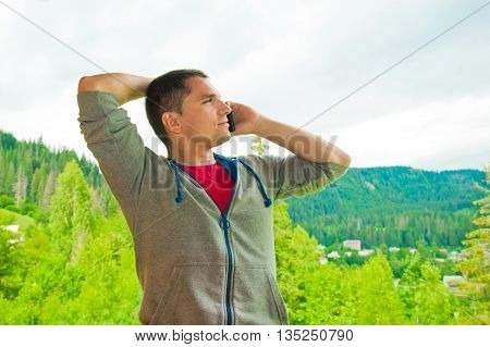 Young man calling on mobile phone. Mountains. Communication conc