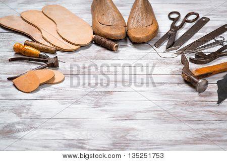 Set of tools for shoemaker on the white wooden background. Copy space.