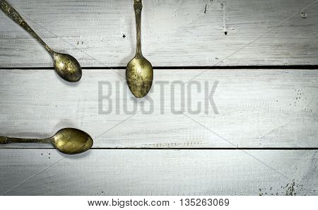 Three old spoons on a white wooden background. Top view