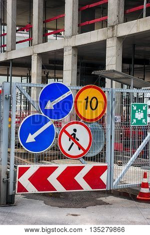 group of road traffic signs on the metal gate of the construction site