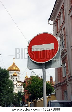 metal round red road stop sign with white stripe in the background of golden dome of orthodox church