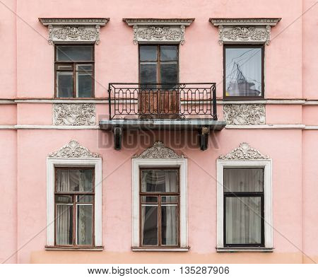 Several windows in a row and balcony on facade of urban apartment building front view St. Petersburg Russia