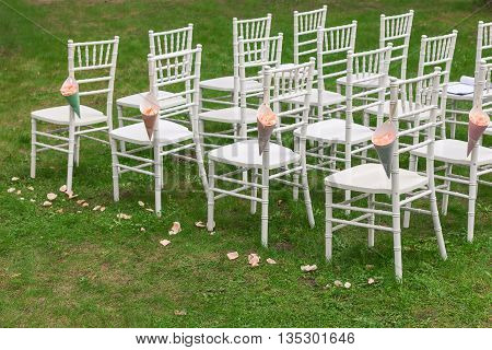 Bags of rose petals on the chiavari chair. Plenty of chairs in the background
