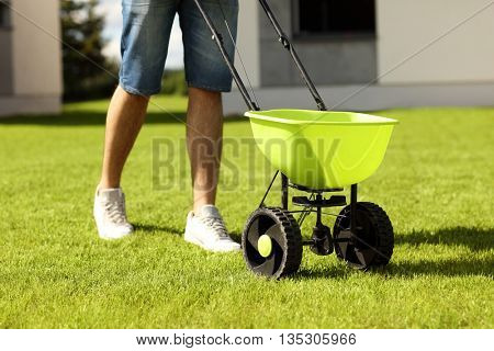 Picture of young man seeding grass in the backyard