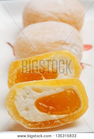 Beautiful japanese fruit mochi rice cakes on white ceramic plate in a cut with delicate mango filling.