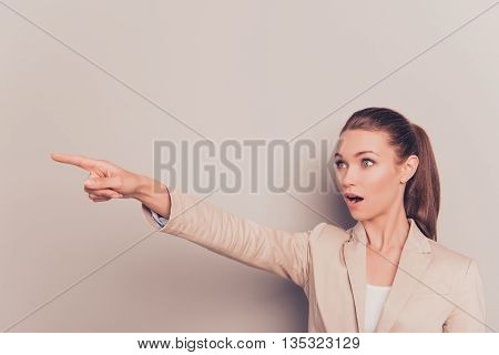 Surprised Pretty Young Businesswoman Pointing With Finger Away