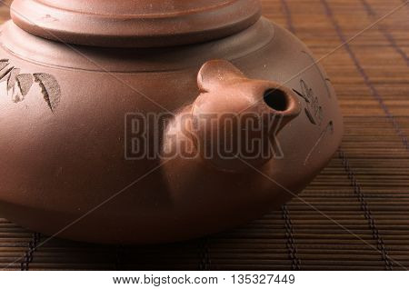 brown Chinese teapot of Yixing clay with traditional ornament on bamboo Mat