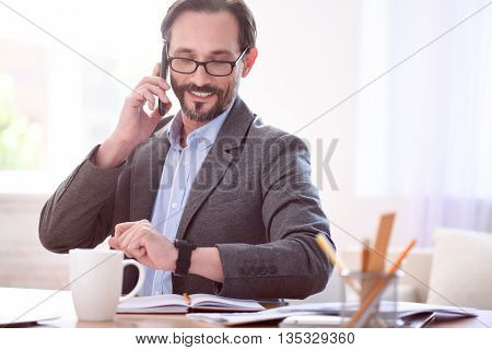 I have time. Glad successful middle aged man talking on the phone and looking at his smart watch