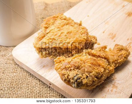 fried chicken on a chopping broad with a glass set on a sack background