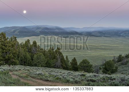full moon setting at dawn over mountains covered by wildfire smoke - North Park, Colorado near Wyoming border (june 20, 2016)