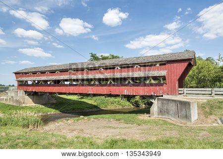 Historic red Bigelow Covered Bridge built in 1873 crosses Little Darby Creek in rural Union County Ohio.