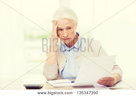 business, savings, annuity insurance, age and people concept - senior woman with papers or bills and calculator writing at home